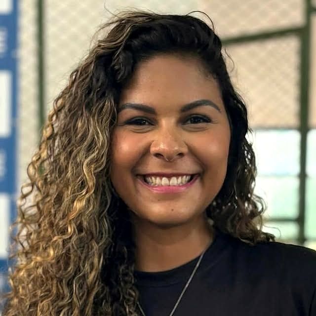 Ju Dantas sorrindo, de cabelo cacheado solto