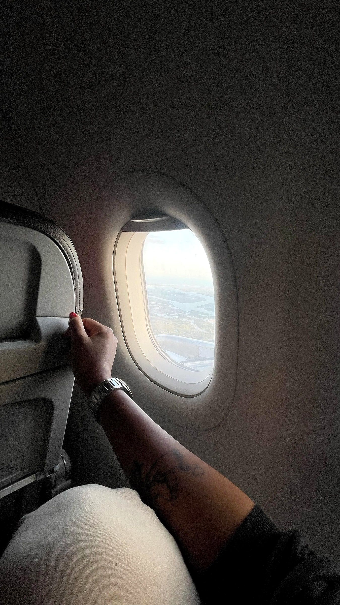 Mão da Ju na janela do avião durante uma viagem
